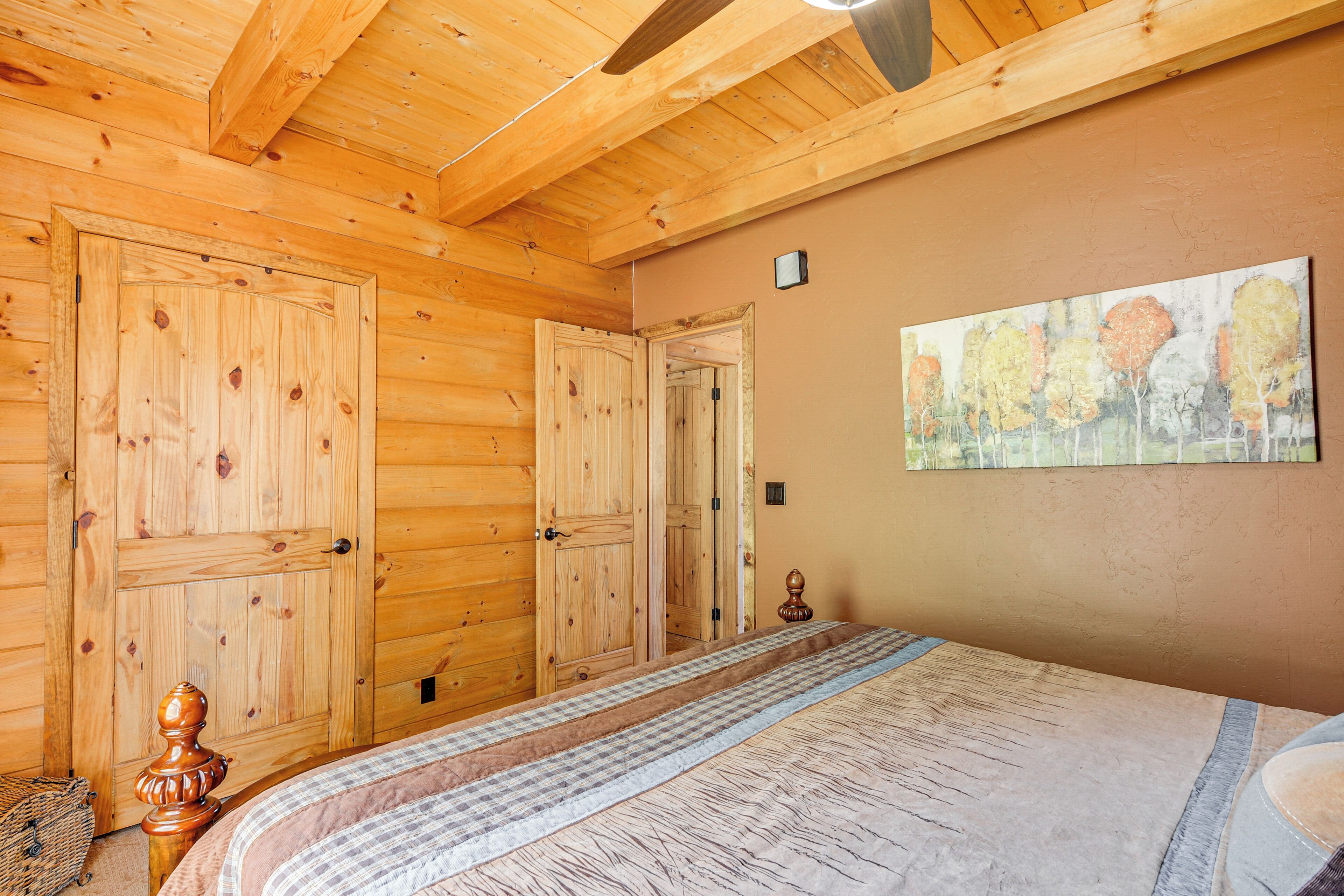Une pièce de style cabane en bois, avec un lit, des portes en bois et un tableau accroché au mur.