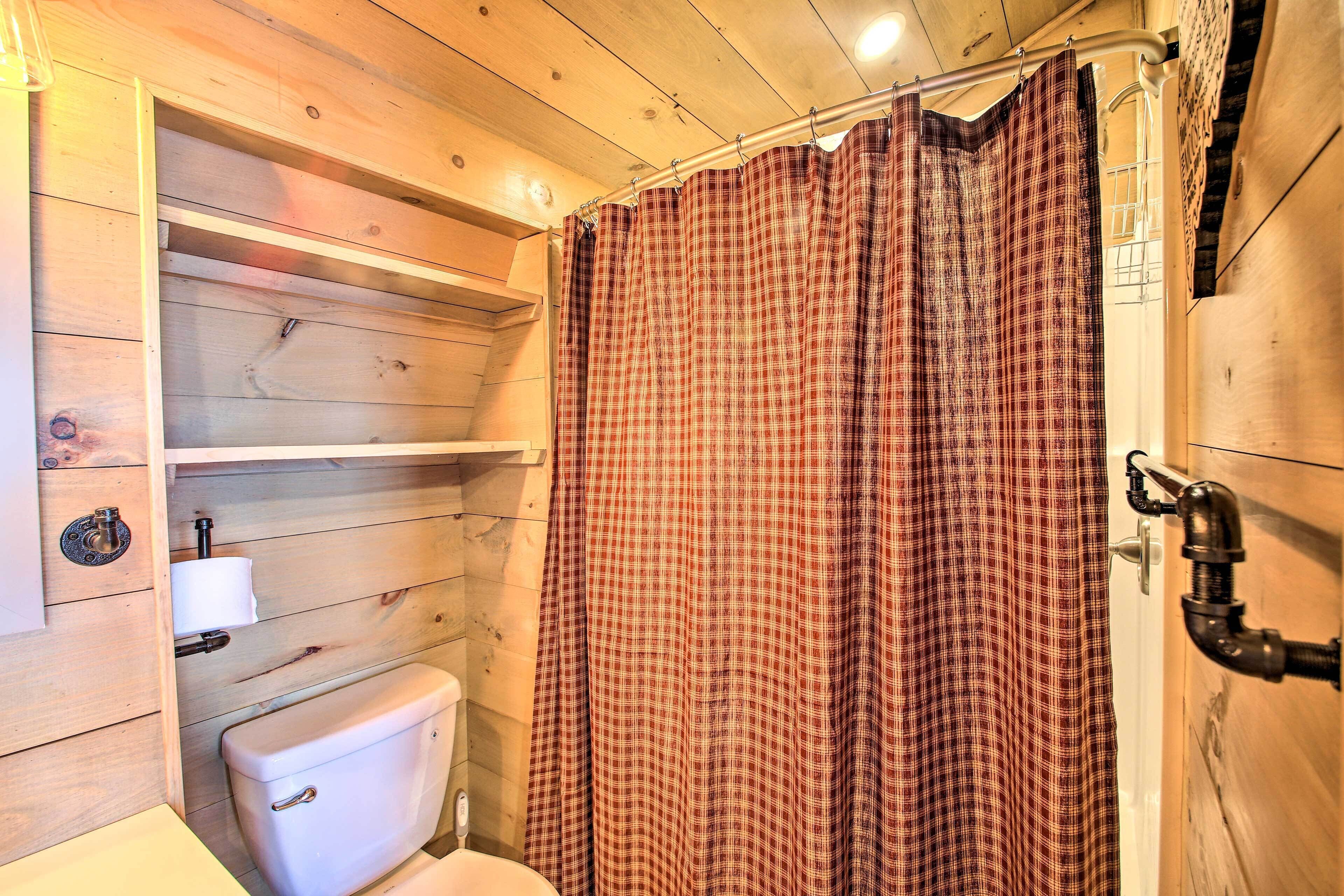 Une salle de bain en bois avec des toilettes, des étagères et un rideau de douche.