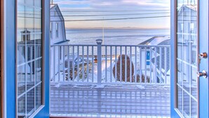 A view from a balcony with a railing, overlooking a body of water and distant land. - Sebago Lake Haven: Water Views, Steps to Shoreline (Sebago)