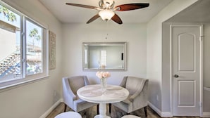 A room with a ceiling fan, a round table with a vase of flowers, two armchairs, and a door. - Palm Desert Resort-style Living: Dog Friendly (Palm Desert)