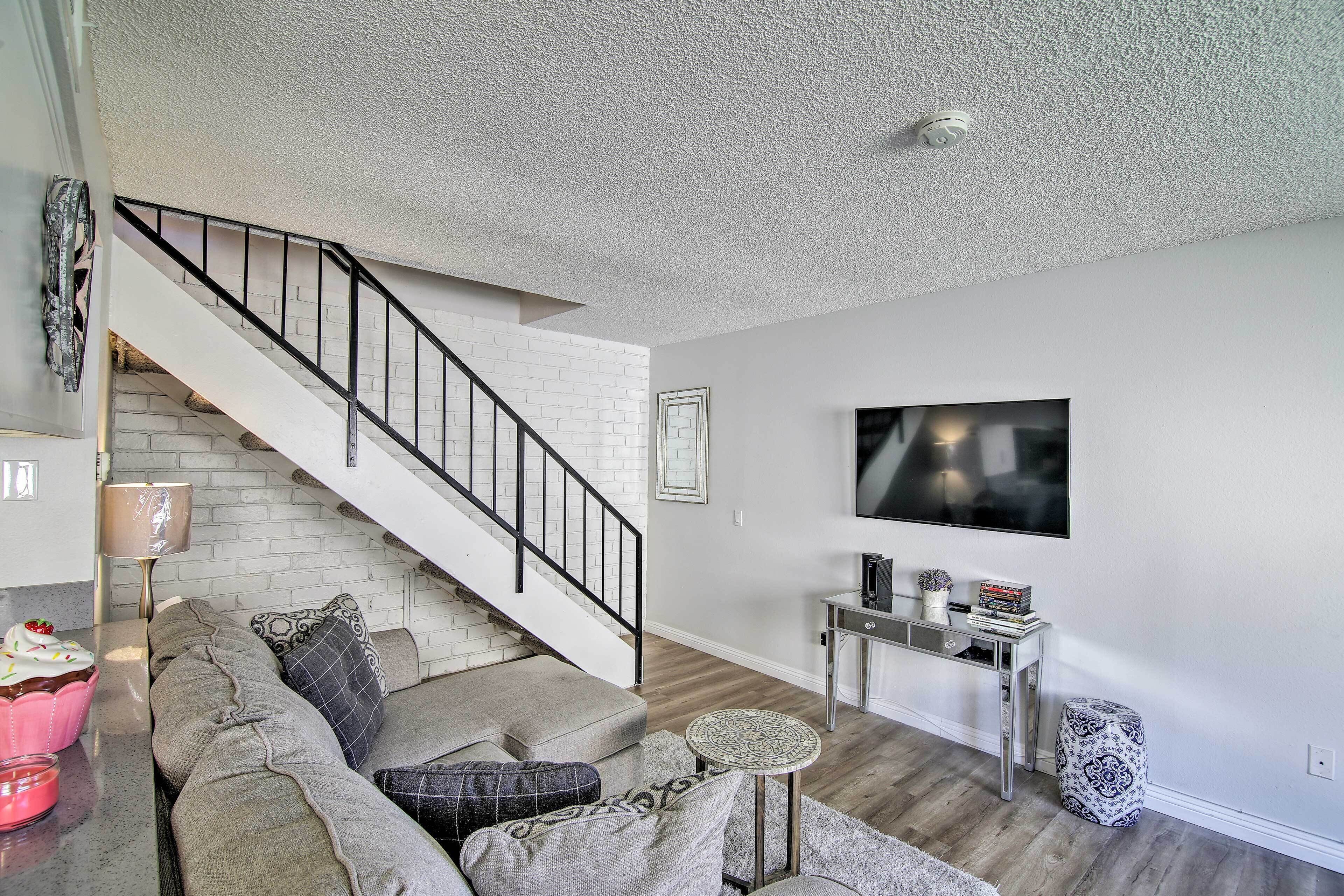 A modern living room with a staircase, a flat-screen TV, and a coffee table.