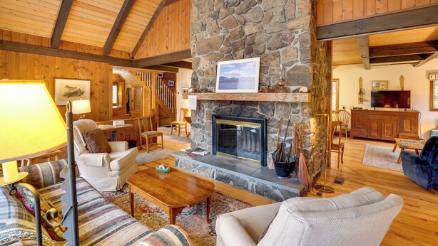 A cozy living room with a stone fireplace, wooden beams, and comfortable seating. - Community Perks: Retreat w/ Thirteenth Lake Access (North River)