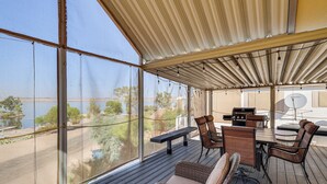 A covered outdoor deck with a view of a lake, a barbecue area, and seating. - Boat Launch + Mtn Views: Lake Havasu Cabin (Lake Havasu City)