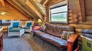 A cozy log cabin interior with a brown leather sofa, wicker chairs, and a wooden ceiling. - Pet-friendly Moab Cabin w/ Mtn Views & Bbq! (Moab)