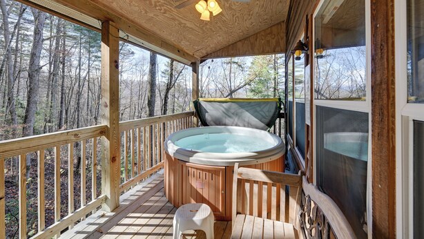 A wooden deck with a hot tub, wooden railings, and a ceiling fan. - Secluded Nantahala 'gone Hunting' Cabin w/ Hot Tub (Bryson City)