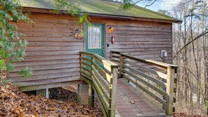 A wooden cabin with a green door, a fire extinguisher, and a wooden staircase leading to a porch. - Secluded Nantahala 'gone Hunting' Cabin w/ Hot Tub (Bryson City)