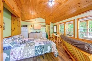 A cozy cabin interior with a bed, a dining area, and a kitchen. - Secluded Nantahala 'gone Hunting' Cabin w/ Hot Tub (Bryson City)