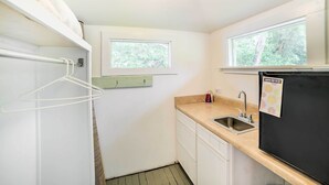 A compact kitchen with a sink, a black refrigerator, and a window providing natural light. - Waterfront Perdido Beach House w/ Canoes & Kayaks! (Elberta)
