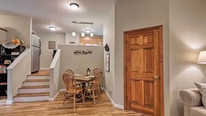 A dining area with a wooden table and chairs, a refrigerator, and a staircase leading to another level. - Unique Ovid Apt w/ Grill on Cayuga Wine Trail! (Ovid)