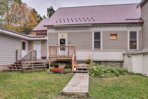 A two-story house with a front porch, a wooden staircase, and a small garden with flowers and pumpkins. - Unique Ovid Apt w/ Grill on Cayuga Wine Trail! (Ovid)