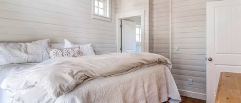 A bedroom with a large bed, wooden flooring, and a loft area with a staircase.