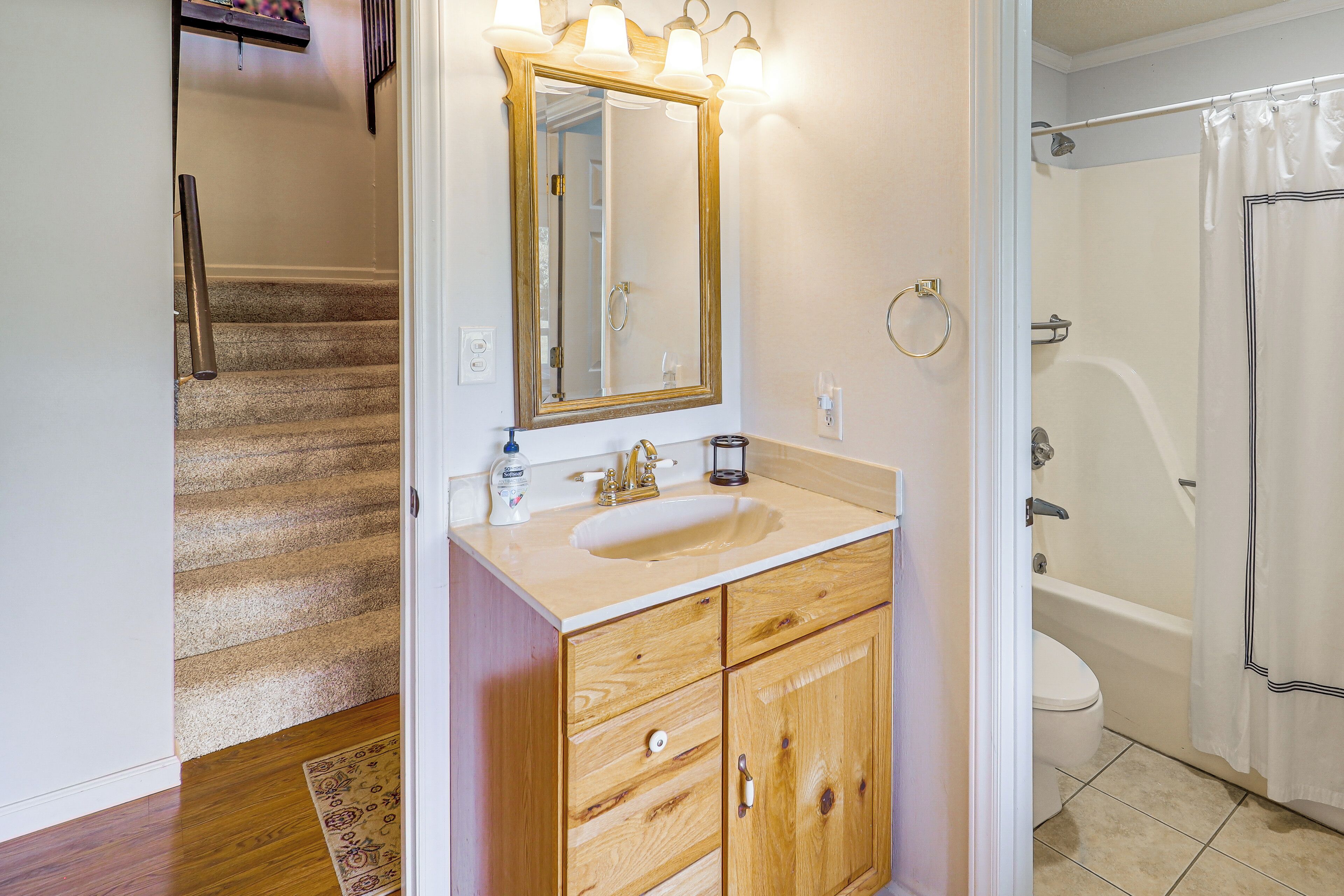 A bathroom with a wooden vanity, a sink, a mirror, and a bathtub.