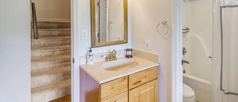 A bathroom with a wooden vanity, a sink, a mirror, and a bathtub.
