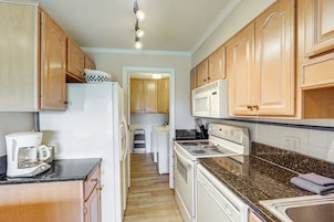 A kitchen with wooden cabinets, a refrigerator, a coffee maker, a stove, and a microwave.