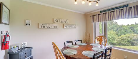 A dining area with a wooden table, chairs, and placemats. There are wall decorations with inspirational phrases and a fire extinguisher on the wall.