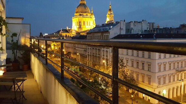 A balcony with a railing overlooking a cityscape at dusk. - Basilica View Apartment With Balcony (Budapest)