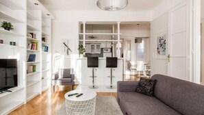 A modern living room with a grey sofa, white coffee table, and a bookshelf. - Basilica View Apartment With Balcony (Budapest)