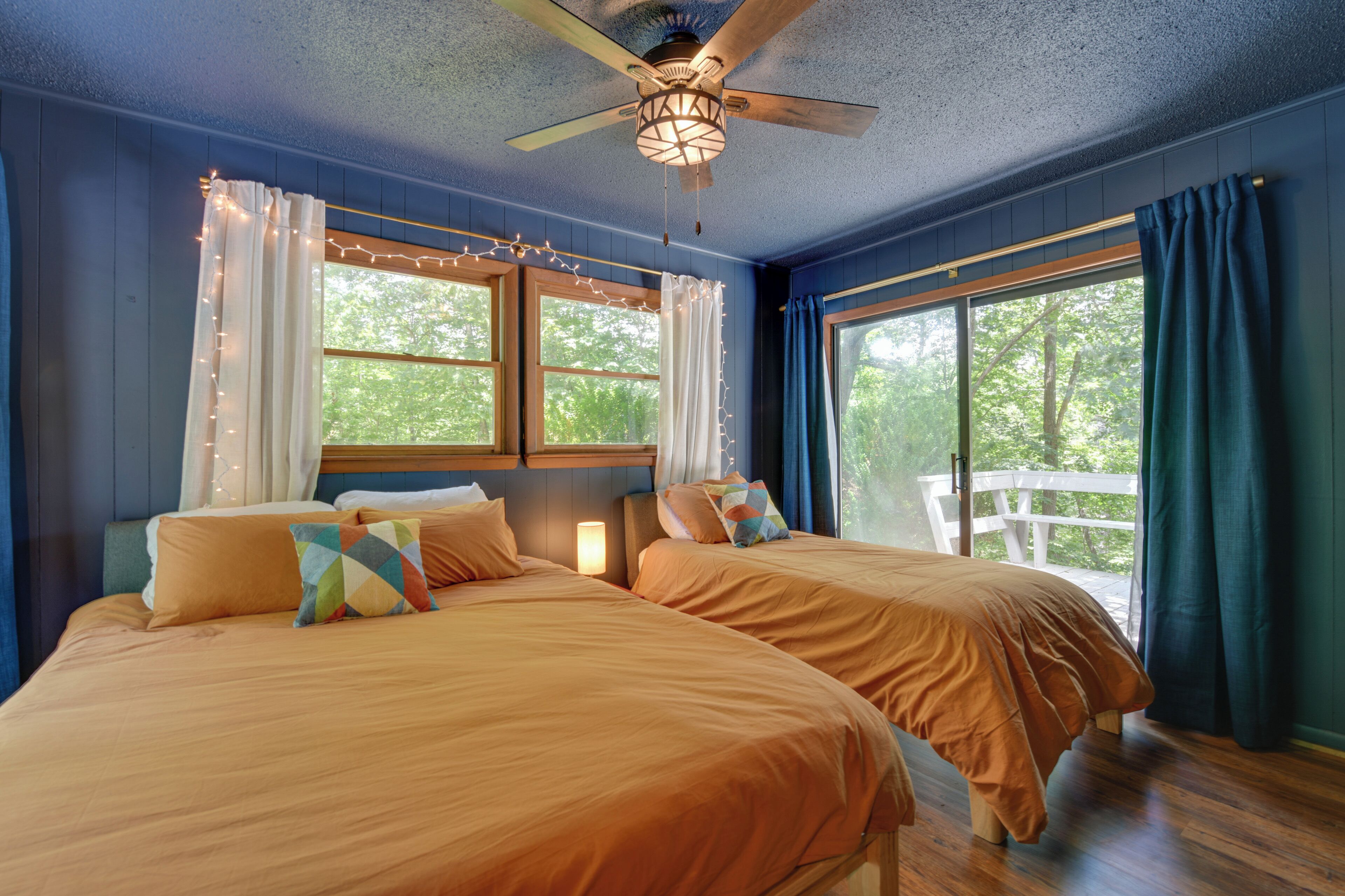 A bedroom with two beds, a ceiling fan, and a window with curtains.