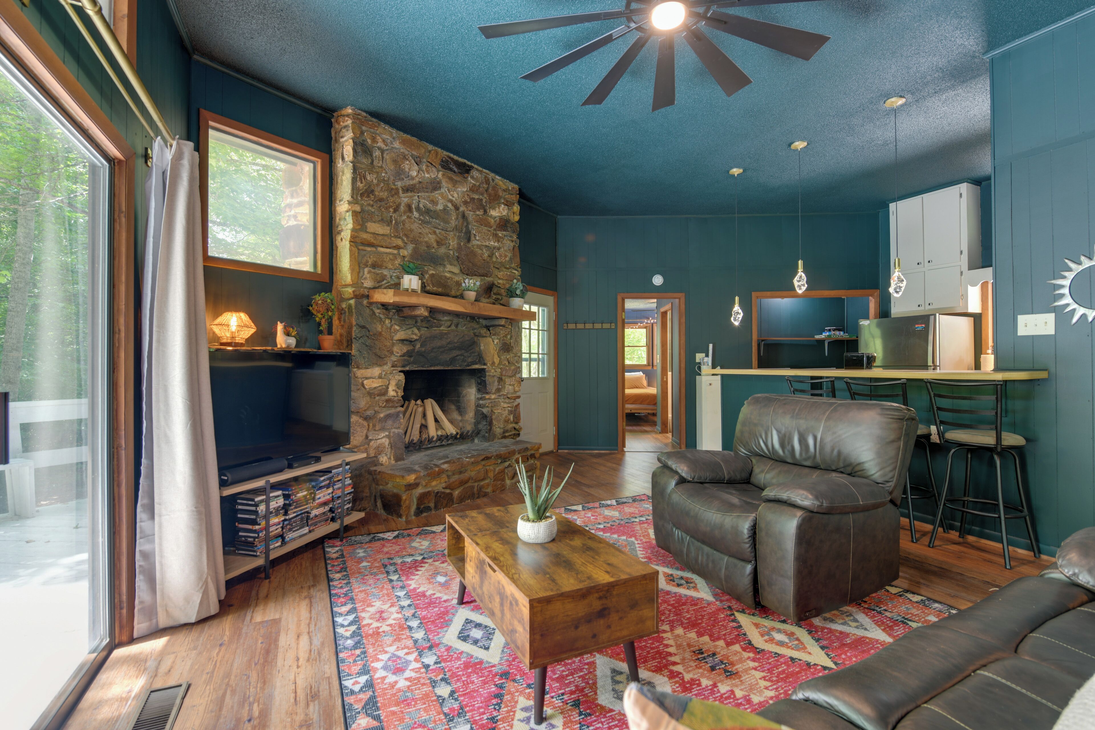 A cozy living room with a stone fireplace, leather sofa, and a wooden coffee table.