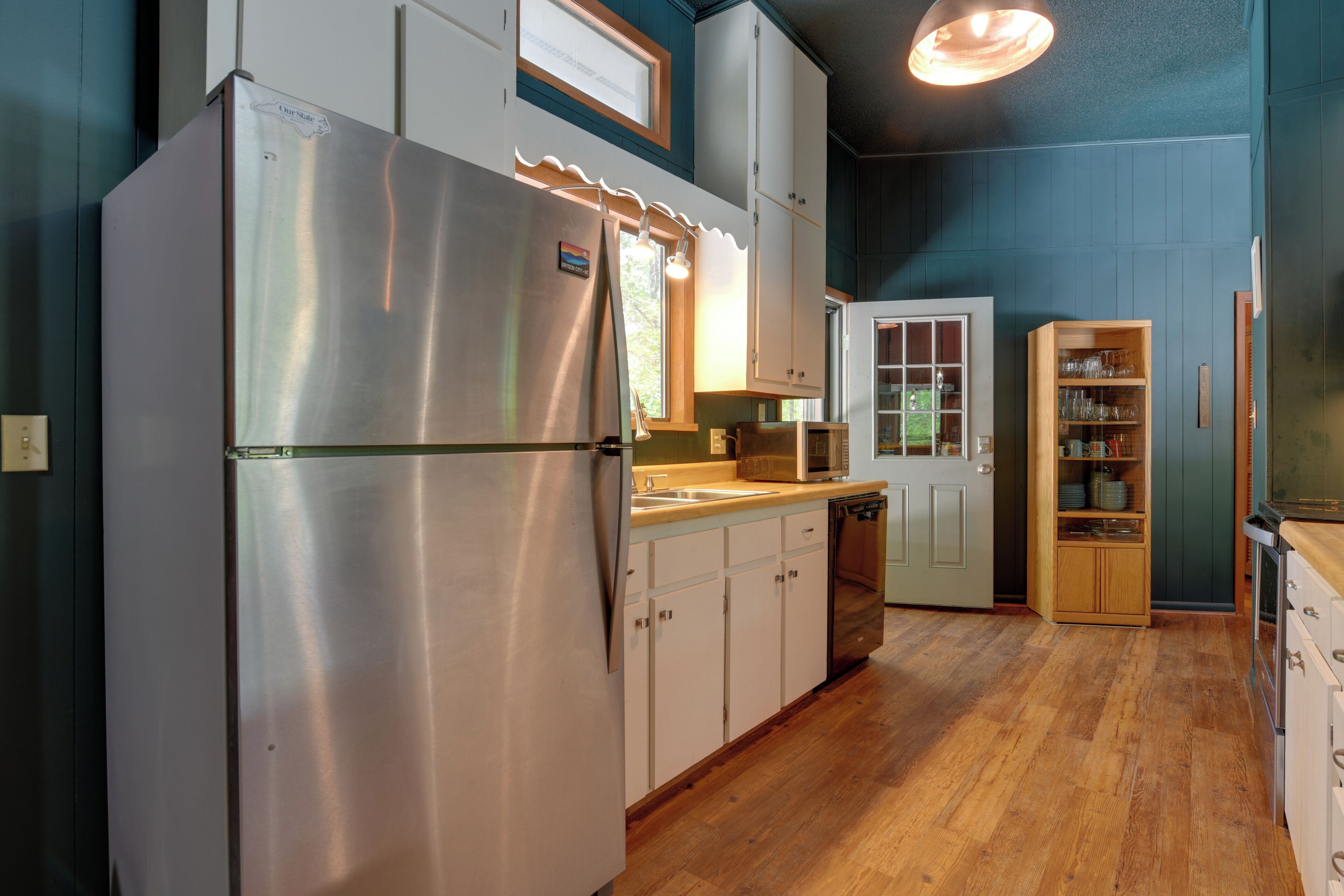 A modern kitchen with stainless steel appliances, wooden cabinets, and a built-in microwave.
