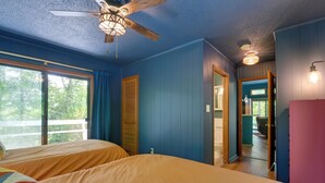 Ein Schlafzimmer mit zwei Betten, einem Deckenventilator und Blick ins Freie.