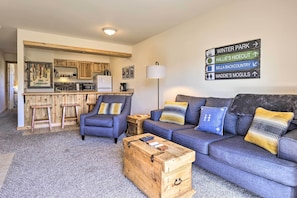 A modern living room with a sofa, coffee table, and a directional sign indicating nearby locations. - Cozy Family-friendly Fraser Condo w/ Mtn Views! (Fraser)