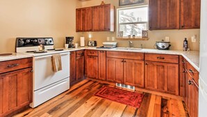 A kitchen with wooden cabinets, a white stove, and a red rug. - Drake Home on Big Thompson River - 3 Mi. to Estes! (Drake)