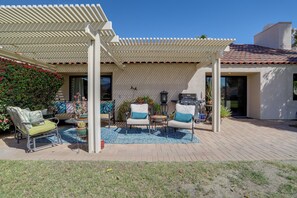 A patio area with outdoor seating, a pergola, and a barbecue grill.