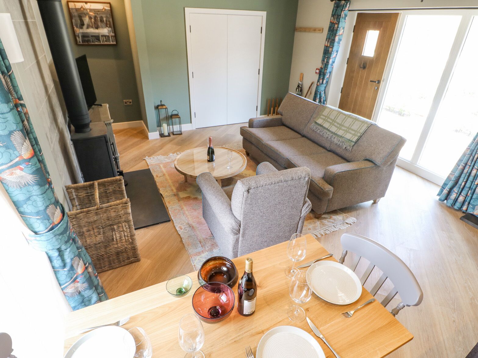 Un salon chaleureux avec un canapé, une table à manger dressée pour deux personnes et une cheminée.