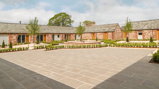 A courtyard with a paved area, stone buildings, and a central landscaped feature. - Bolton Cottage (Appleby-in-Westmorland)