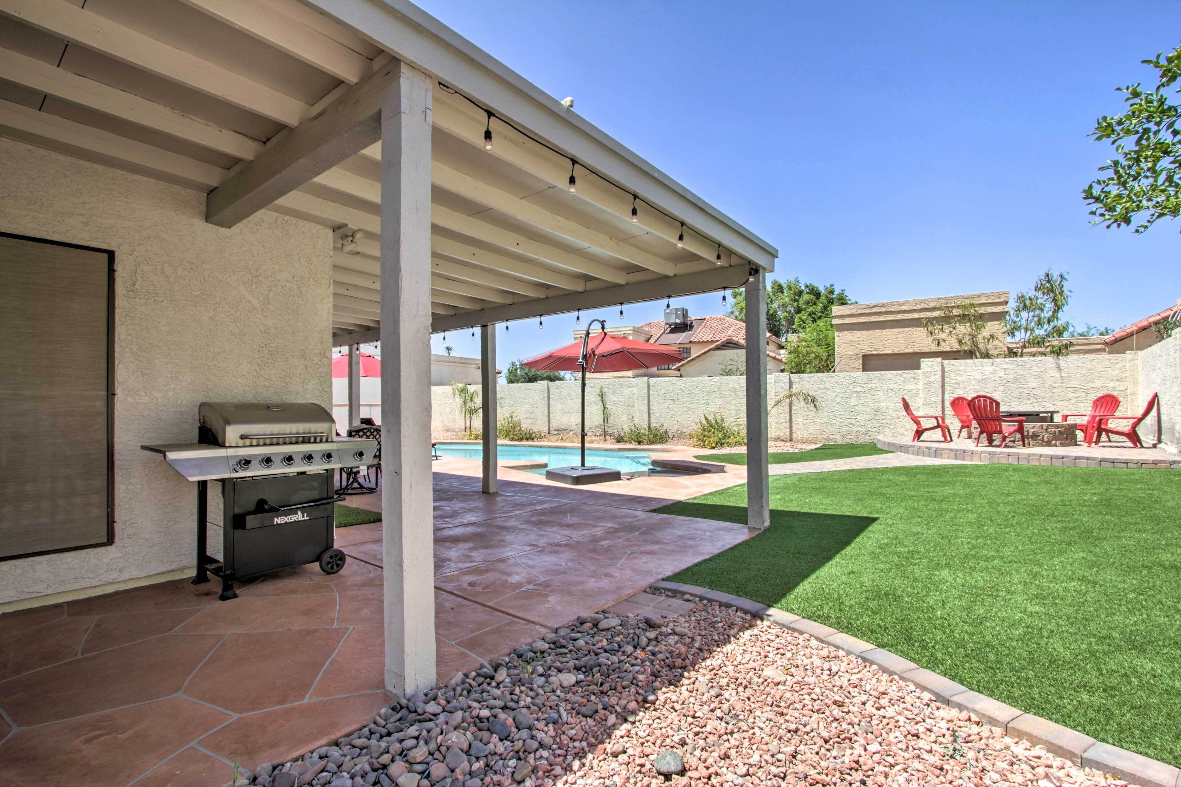 A covered patio with a grill, a swimming pool, and a landscaped yard.