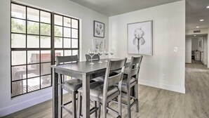 A dining area with a large window, a table with chairs, and framed artwork on the walls. - Hot Tub! Family-friendly Home, 8 Mi to Westgate (Glendale)