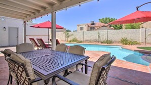 A covered patio with a pool, outdoor furniture, and red umbrellas. - Hot Tub! Family-friendly Home, 8 Mi to Westgate (Glendale)