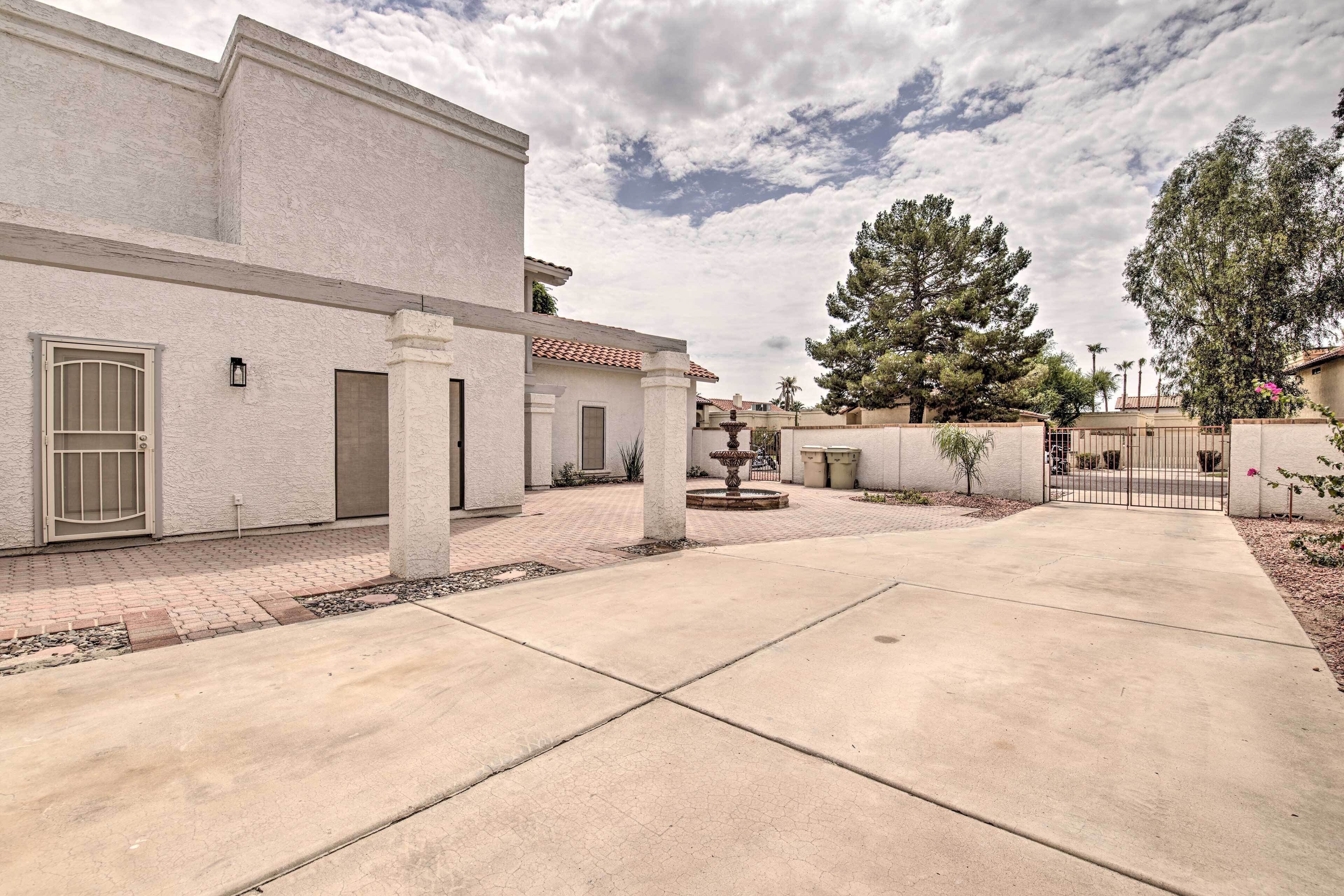 Zona residencial con camino de entrada pavimentado, una fuente y una entrada con portón.