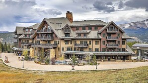 A multi-story hotel with balconies, a pool, and a mountainous backdrop. - Ski-in/ski-out Breckenridge Resort Condo at Peak 7 (Breckenridge)