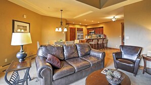 A living room with a leather sofa, a coffee table, and a dining area in the background. - Ski-in/ski-out Breckenridge Resort Condo at Peak 7 (Breckenridge)