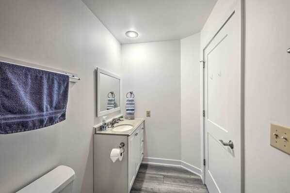 Un baño estrecho con inodoro, lavabo y espejo.