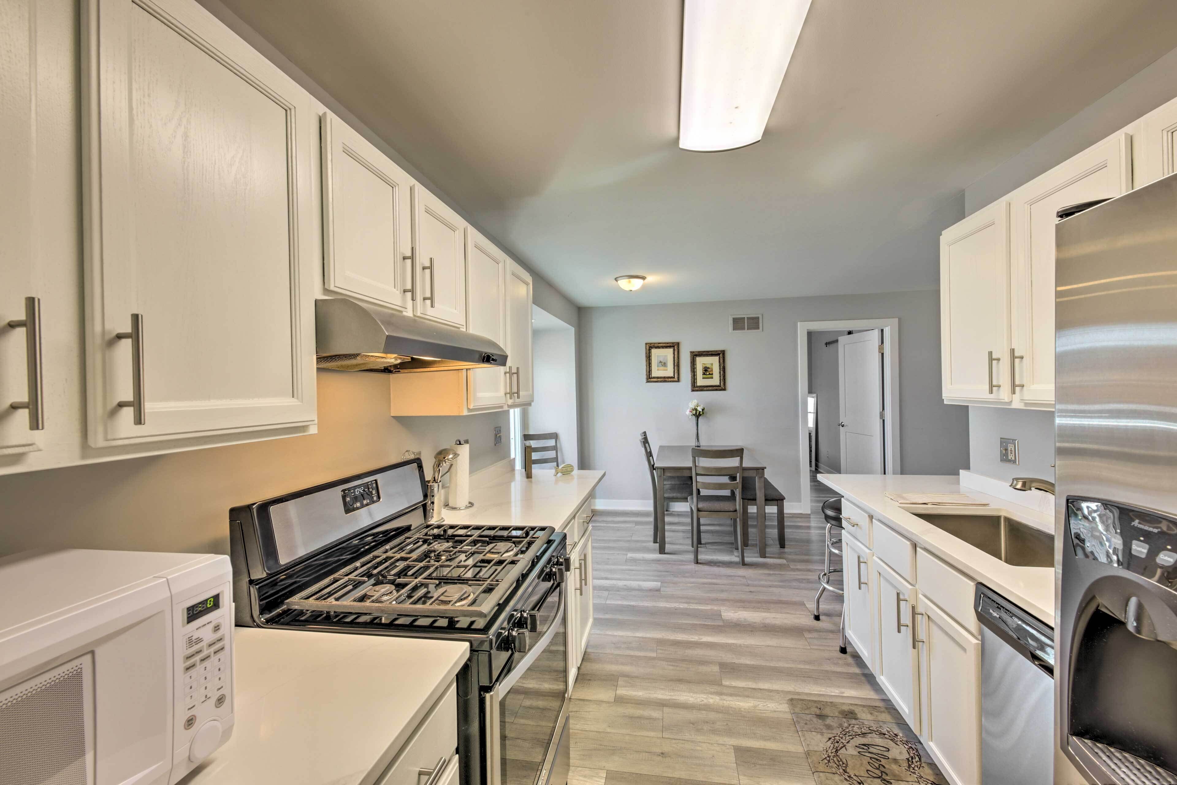 A modern kitchen with white cabinetry, a gas stove, a built-in oven, and a stainless steel refrigerator.