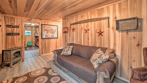 A cozy cabin interior with a wooden floor, a brown leather couch, a map on the wall, and a fireplace. - Remote Kentucky Cabin w/ Fire Pit & 2 Ponds (New Concord)