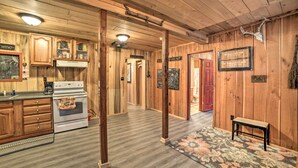A wooden interior with a kitchen, a dining area, and a hallway leading to a door labeled "EAT UP HUNT". - Remote Kentucky Cabin w/ Fire Pit & 2 Ponds (New Concord)