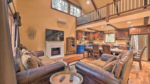 A spacious living room with leather sofas, a fireplace, and a dining area with wooden furniture.