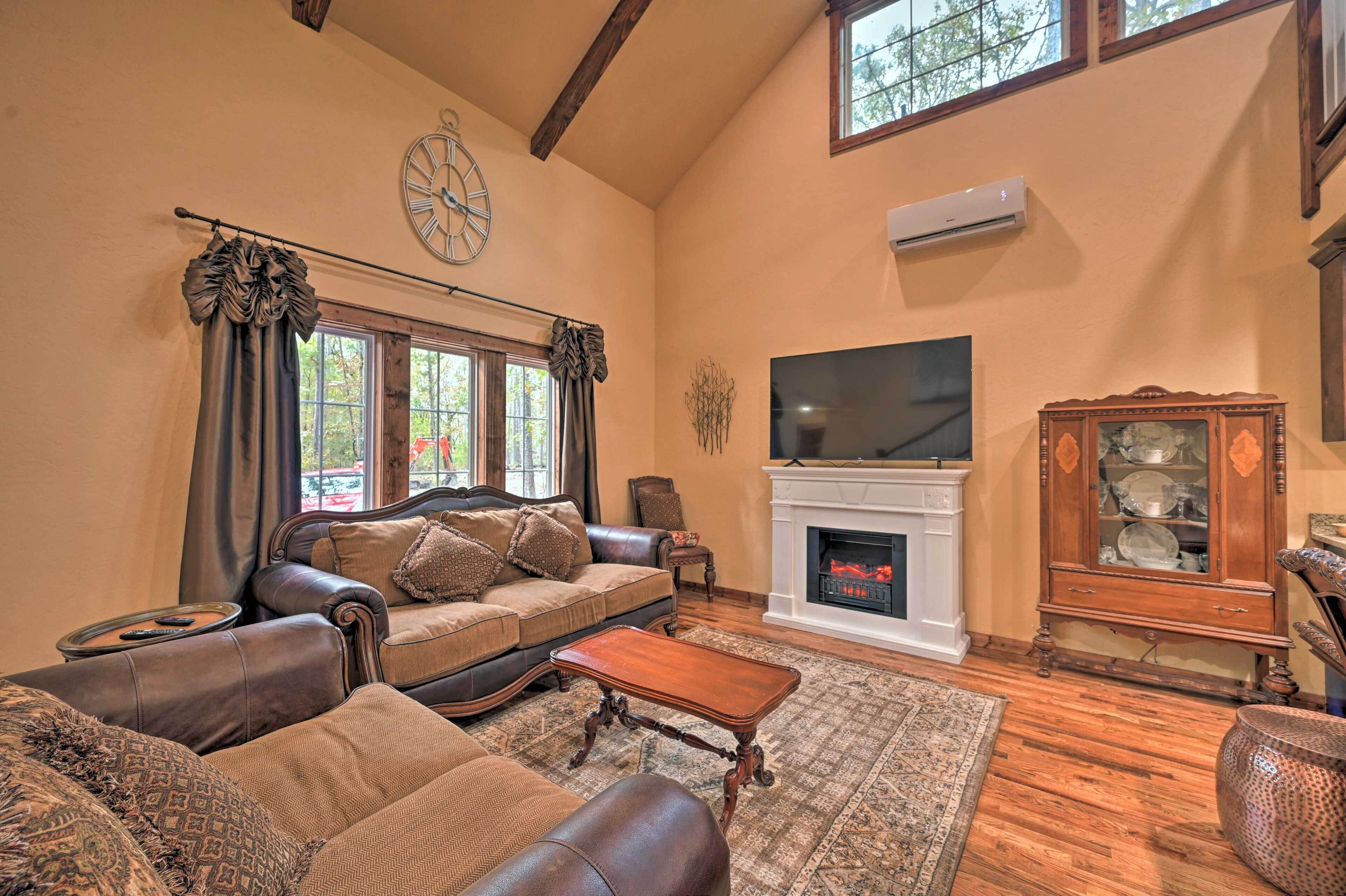 A living room with a fireplace, leather sofas, a television, and a clock on the wall.