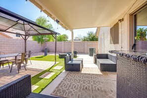 Une terrasse extérieure dotée d’un espace salon couvert, d’une table à manger et d’un tapis à motifs.