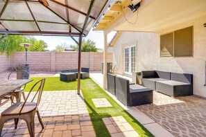 Un patio couvert avec une table et des chaises, un espace salon intégré et une petite pelouse.