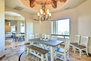 A dining area with a large wooden table, white chairs, and a chandelier.