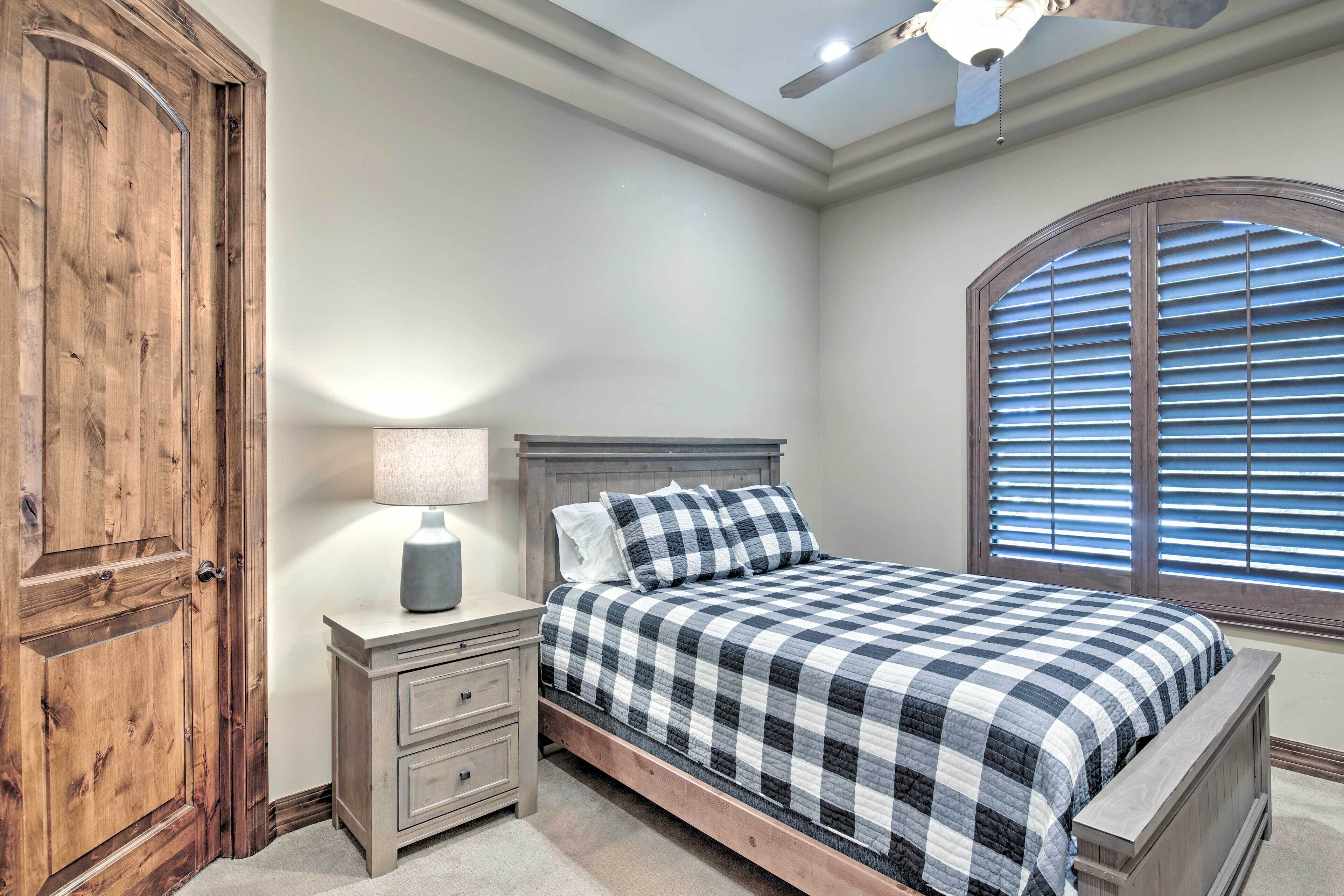 Une chambre à coucher avec un lit en bois, une table de chevet avec des tiroirs, une lampe et une fenêtre avec des stores.