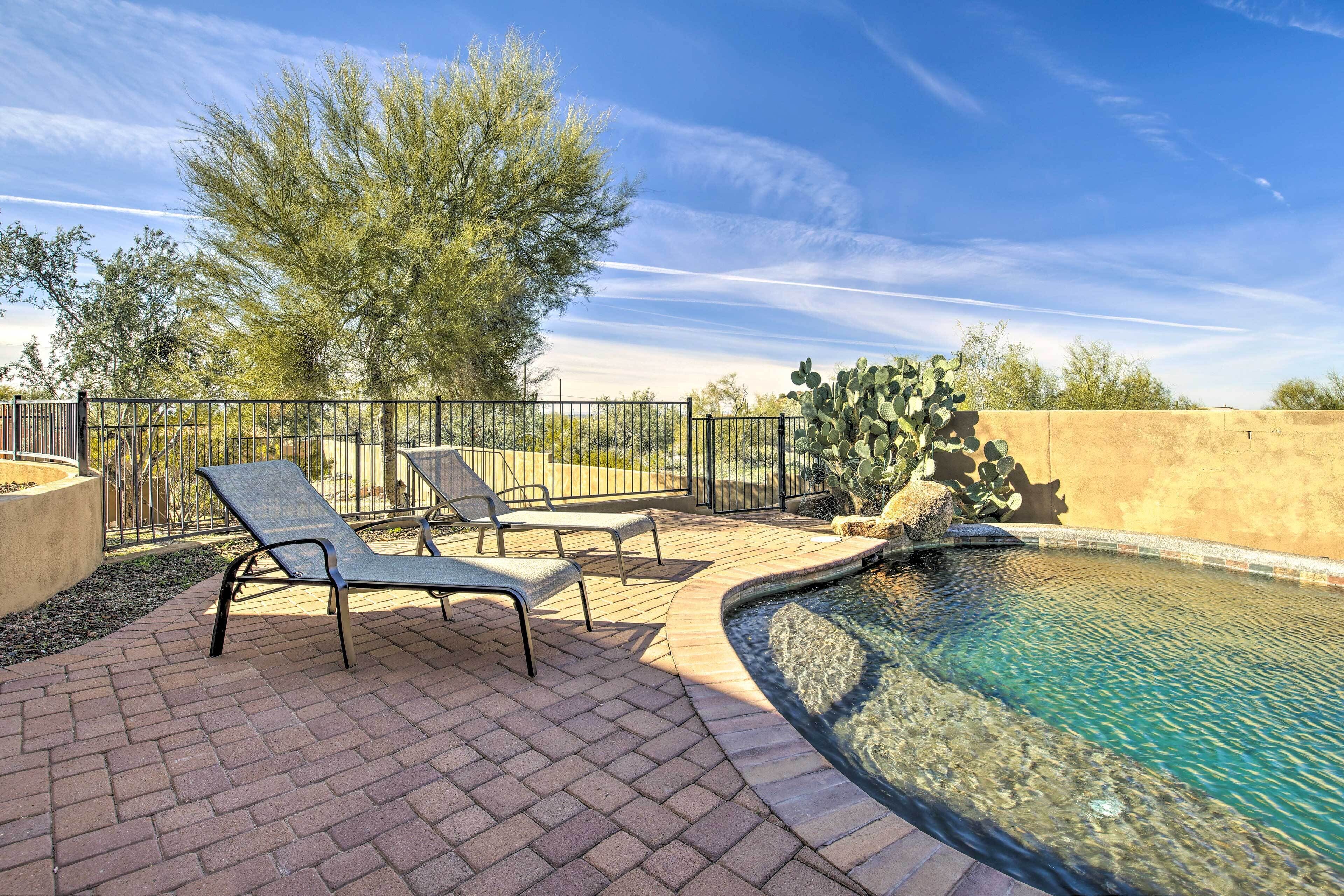 A pool area with lounge chairs and a cactus plant.