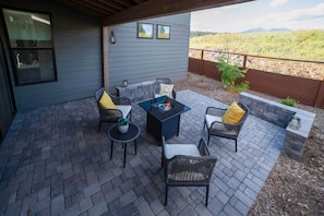 Un patio exterior con una chimenea, asientos y vistas al paisaje.