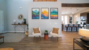 A spacious living area with a high ceiling, wooden beams, and a modern kitchen in the background. - Modern Flagstaff Escape w/ Grill, 3 Mi to Downtown (Flagstaff)