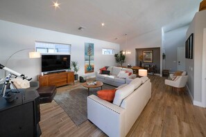 Amplia sala de estar con sofá, televisor y comedor con mesa y sillas.